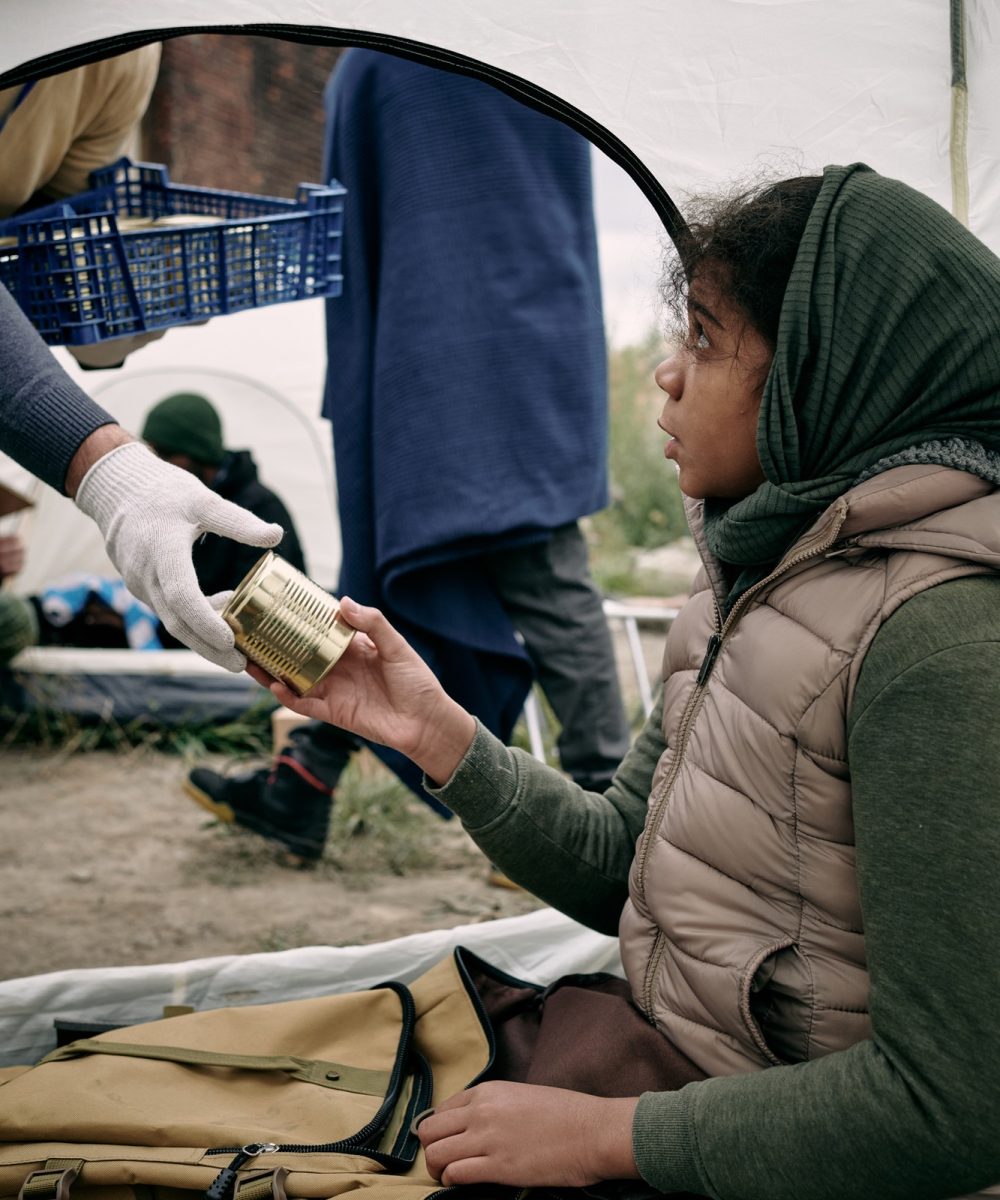 hungry-girl-refugee-taking-tinned-food-from-gloved-hand-of-volunteer.jpg